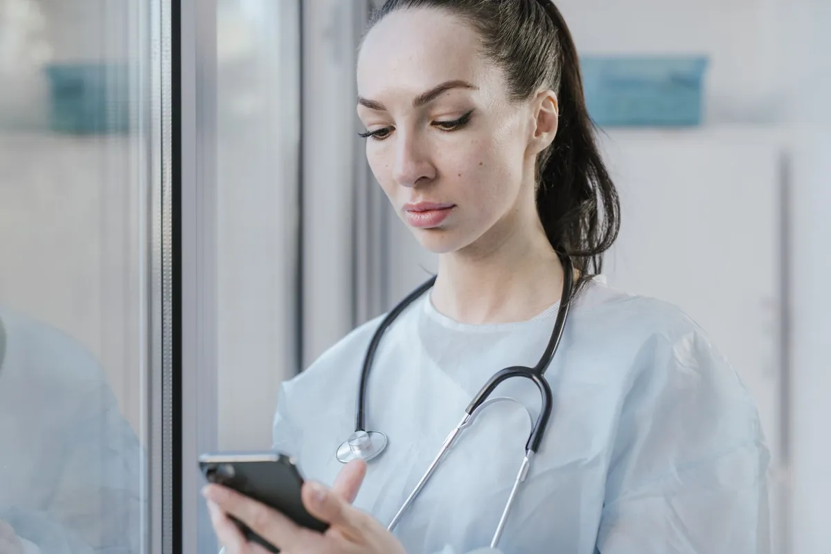 Médica usando o celular no hospital - automação de WhatsApp para consultórios na Poupar AI