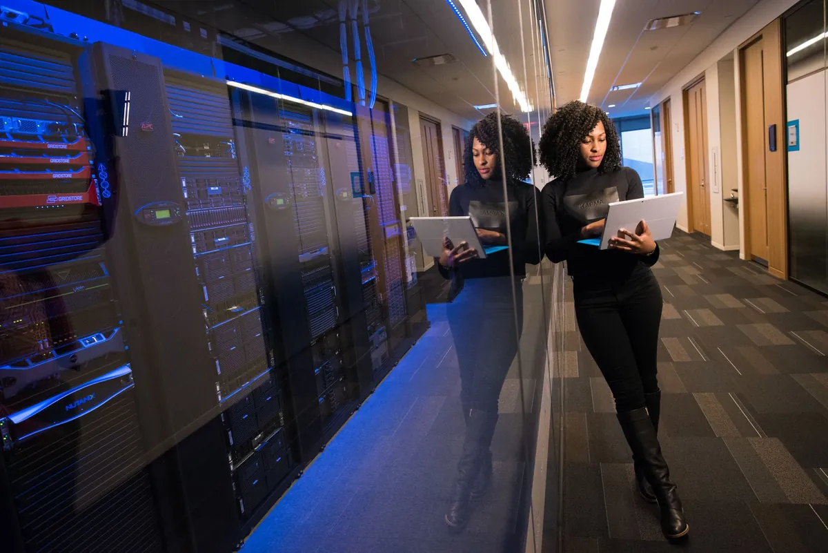 Mulher usando notebook diante de servidores de data center - G4 OS instalado no computador ou Poupar AI na nuvem